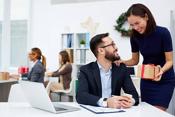 Congratulating with Christmas Young businesswoman giving her colleague Christmas present at office business gifts stock pictures, royalty-free photos & images