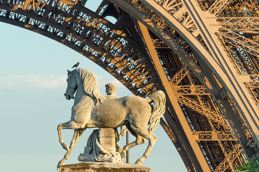 Old horse statue on the Pont d'Iéna and part of an arch of the Eiffel tower, Paris France.