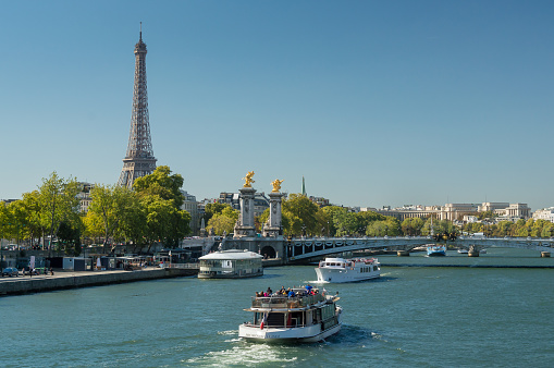 Some boats on the river Seine near the Pont Alexandre III. In the distance the Eiffel tower.