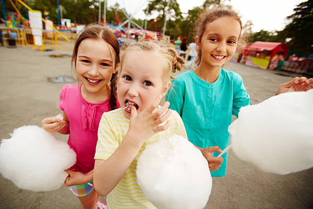 Children in the park Happy girls eating cotton candy in the park child cotton candy stock pictures, royalty-free photos & images
