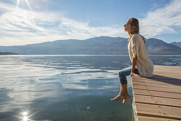 istock Young woman relaxes on lake pier 502873676