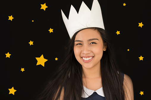 Happy Vietnamese girl wearing paper crown against star sky