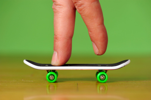 Concept macro image with two human fingers on miniature skateboard.