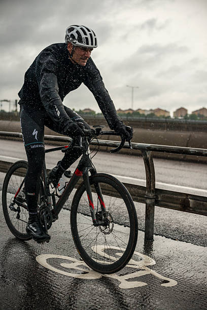 Riding bike in rain - Stockholm, Sweden Stockholm, Sweden - June 23, 2015: A man cycles during a summer rain on Skanstullsbron, a bridge connecting the island of Södermalm to the southern district Johanneshov, in Stockholm, Sweden. sodermalm photos stock pictures, royalty-free photos & images