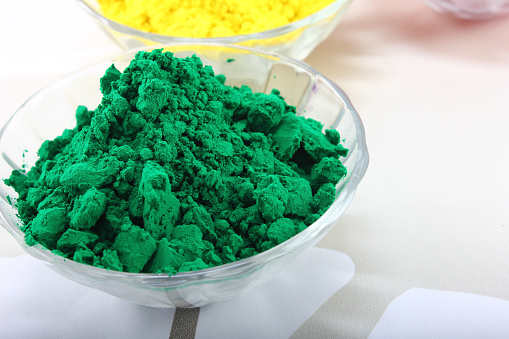 Green and yellow colour dyes in bowl for holi festival