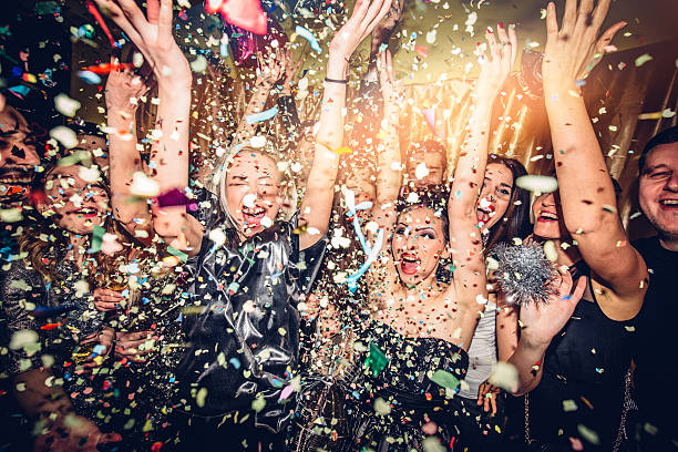 Party! Confetti falling over a smiling group of people on a dance floor of a nightclub new years eve parties stock pictures, royalty-free photos & images