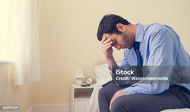 Depressed Man Sitting Head In Hands On His Bed Stock Photo - Download Image Now - Blue, Depression - Sadness, Loneliness