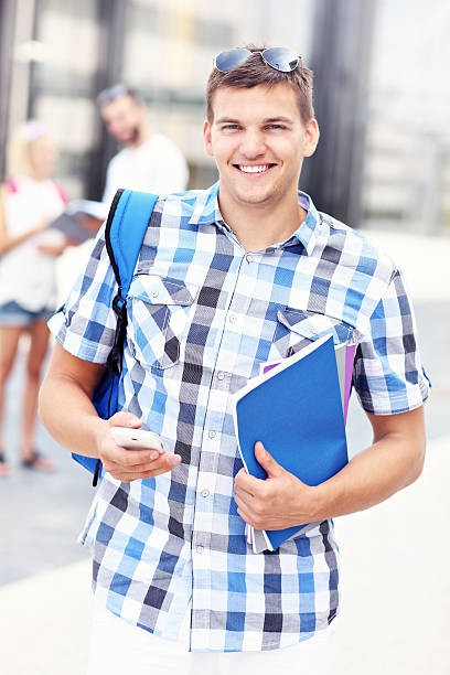 istock Happy student standing in the campus with his smartphone 502914430