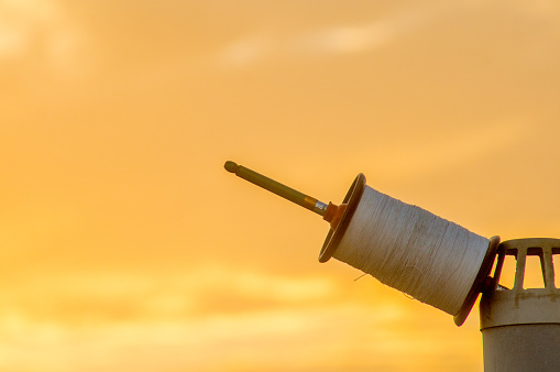 Indian spool, charkhi, used in the sport of kit fighting set against a colorful out of focus background. The thread shown here is the non abrasive or cutting sadda thread.