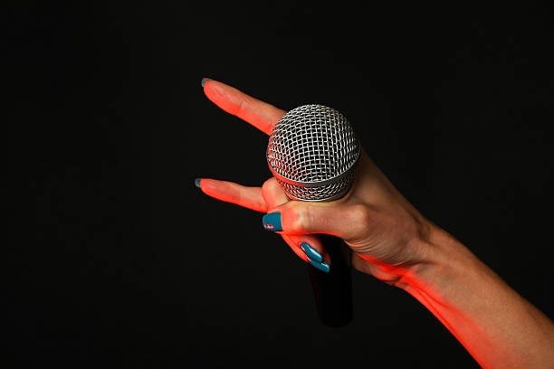 istock Woman hand with microphone and devil horns on black 502919616