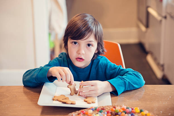 istock Young boy surprised playing with gingerbread cookies at home. 502922506