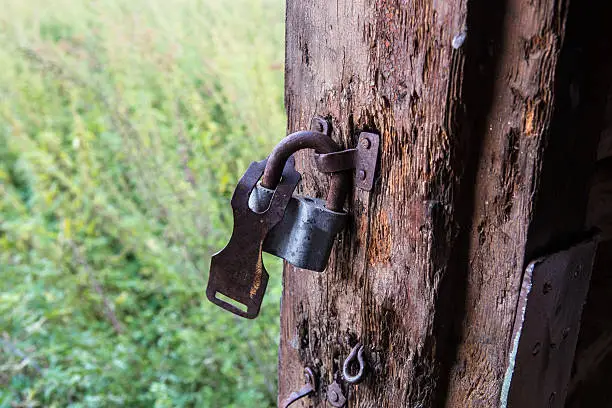 old door slip-up with broken lock and view in field with grass