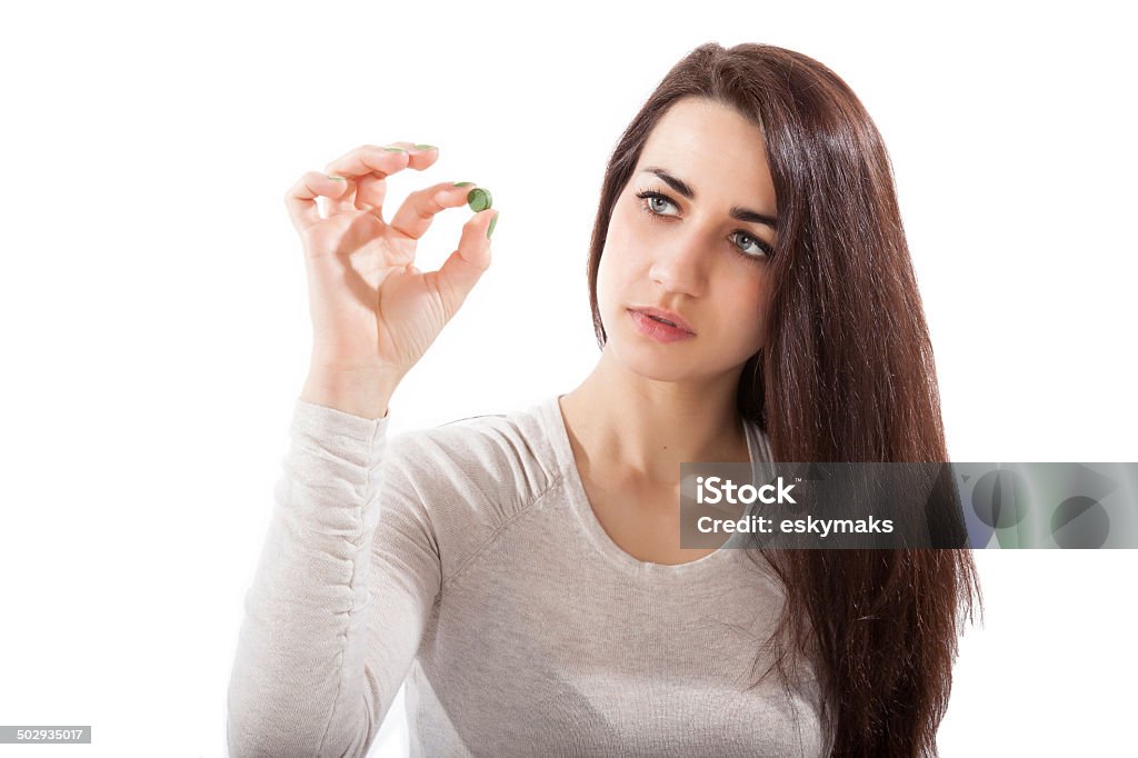 Chlorella. Beautiful girl in her 20s holding green chlorella and spirulina pill isolated on white background. Healthy eating, green superfood. 20-29 Years Stock Photo