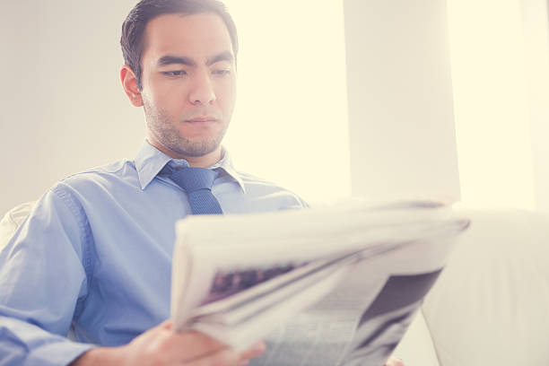 istock Serious handsome businessman reading newspaper 502936129