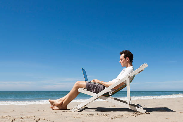 istock Happy young freelancer working online with laptop on a beach 502937794