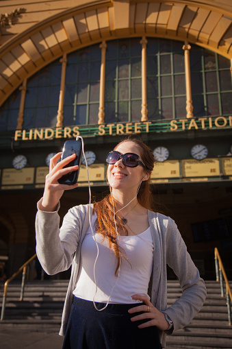 Close up of a young woman taking a selfie at Flinders Street Station. This is an iconic meeting point in the city in Melbourne, Australia.
