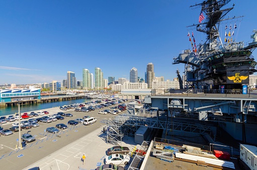 San Diego, United States of America - February 24, 2014: The historic aircraft carrier, USS Midway Museum moored in Broadway Pier in Downtown San Diego, Southern California, United States of America and the skyline. A battleship commissioned after the World War II.