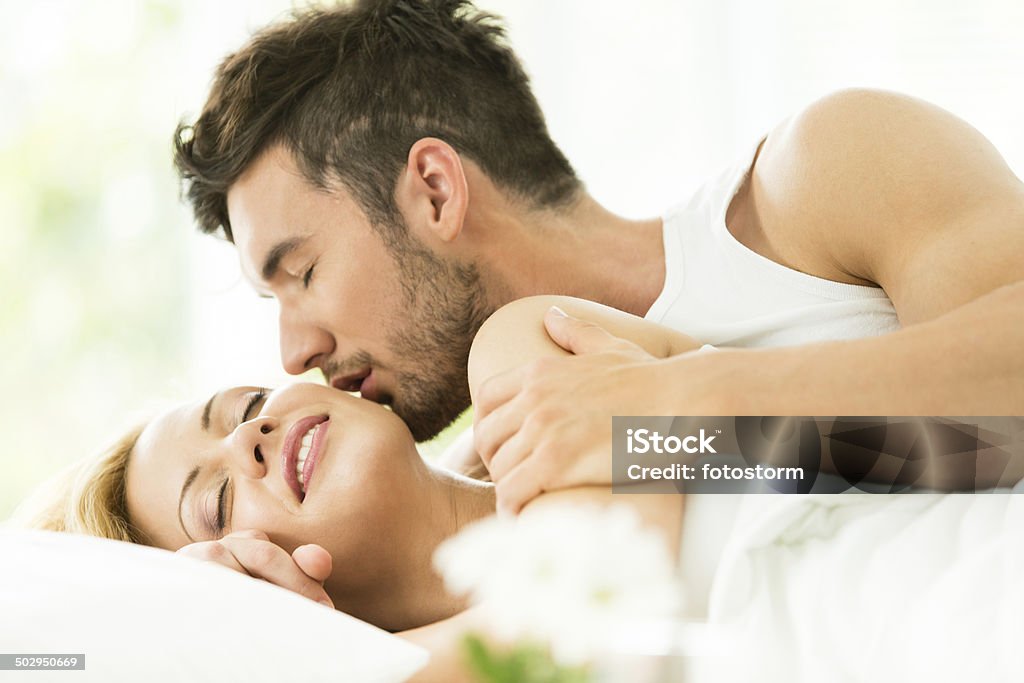 Hombre Besando a la mujer en la cama - Foto de stock de Cama libre de derechos