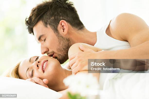 Hombre Besando A La Mujer En La Cama Foto de stock y más banco de imágenes de Cama - Cama, Despertar, Mujeres