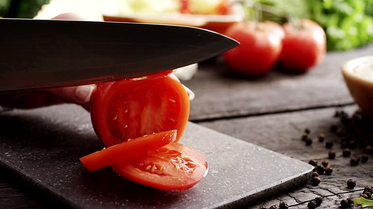 Woman's hands cutting tomato