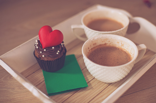 Two Cups of coffee,a note and heart shaped candy on tray in humans hands,Valentine's day