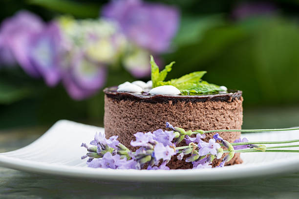 Chocolate lavender mousse cake decorated with mauve culinary lavender flowers in a garden setting