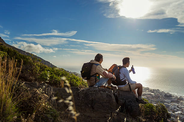 istock Hikers looking at sea while sitting on rocks 502970762