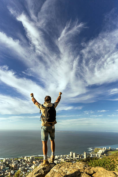 istock Hiker standing with arms raised on cliff 502970998