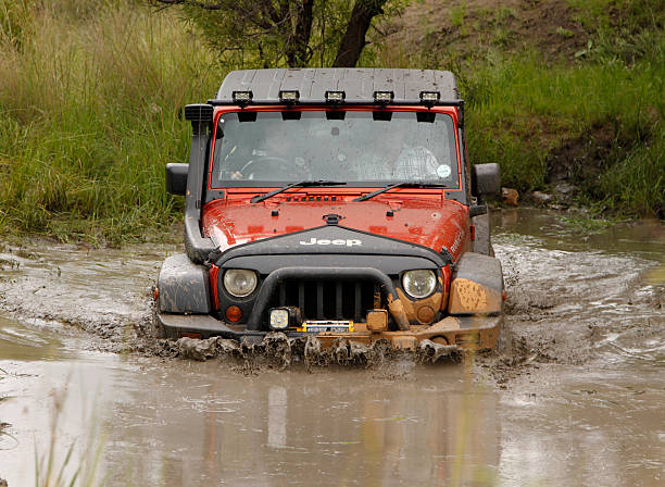 クラッシュオレンジのジープルビコン crossing マディ池 - off road vehicle 4x4 jeep mud ストックフォトと画像