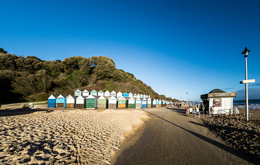 Bournemouth, UK - December 29, 2015: Rows of beach huts at Middle Chine in Bournemouth on a sunny winters day. A small kiosk on the right serves people with drinks and snacks. Logos on the beach huts for local ice-cream.