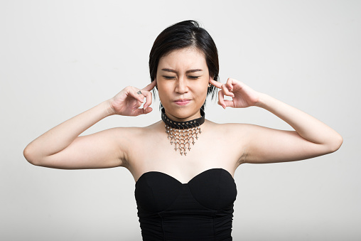 Stressed Asian woman covering ears horizontal studio shot