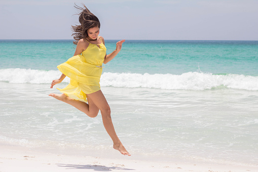 Happy young woman jumping on the beach