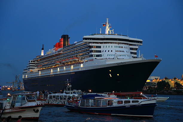 Hamburg, Germany - July 19, 2014: The  transatlantic Passenger ship / cruise liner Queen Mary from Cunard Line leaves Hamburg harbour in Germany followed by smaller boats ands ships in the harbour and fireworks to celebrate her 10 years jubilee in hamburg Saturday July 19th 2014.
