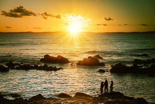 Salvador, Brazil - August 24, 2015: three woman silhouettes standing in the water at sundown hour over ocean of Salvador Brazil