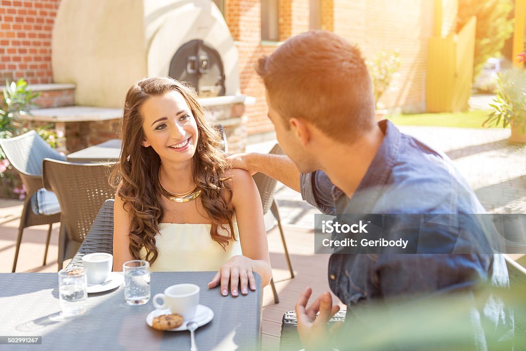 Young couple talking on the terrace of  restaurant Young couple talking on the terrace of the restaurant, while eating Adult Stock Photo