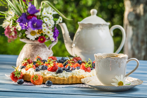 Fruit tart served with coffee in the summer garden
