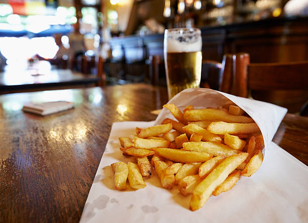 Potatoes fries in a little white paper bag Potatoes fries in a little white paper bag on wood table in brussels pub belgian culture photos stock pictures, royalty-free photos & images