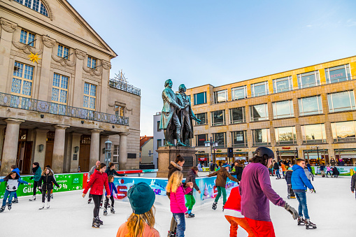 Weimar, Germany - December 19, 2015: people in front of Goethe and SChiller monument enjoy ice skating in Weimar, Germany. Schiller and Goethe were lifetime friends.