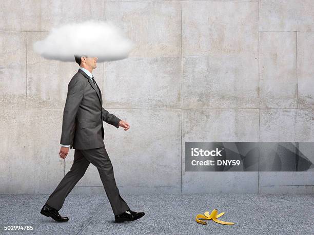 Businessman With Head In Clouds With Banana Peel In Path Stock Photo - Download Image Now