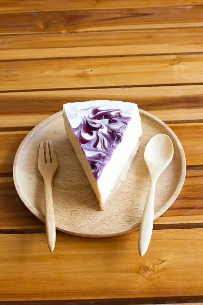 Blueberry cheesecake on wooden plate.