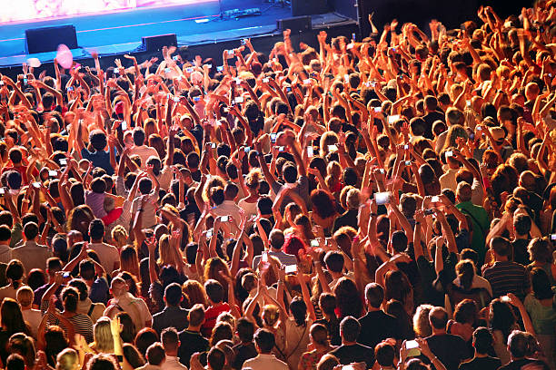 istock Crowd of people at concert with hands raised watching stage 502996465
