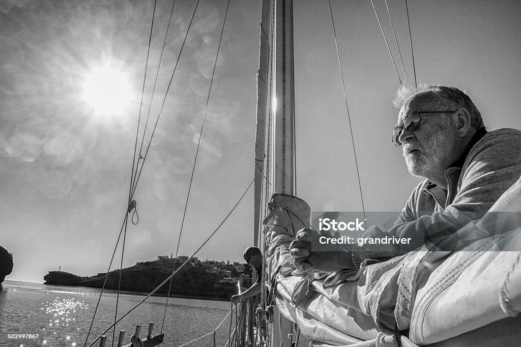 Man on Sailboat Black and white shot of a man on a sailboat on the ocean Business Person Stock Photo