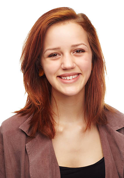 Close-up of a young girl with curly red hair smiling at the camera.