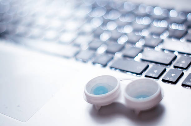 contact lenses laying on computer keyboard stock photo