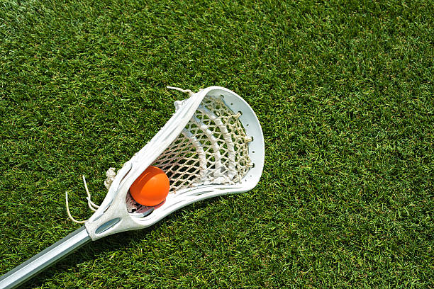 istock Orange ball and white Lacrosse stick on artificial turf 503016354