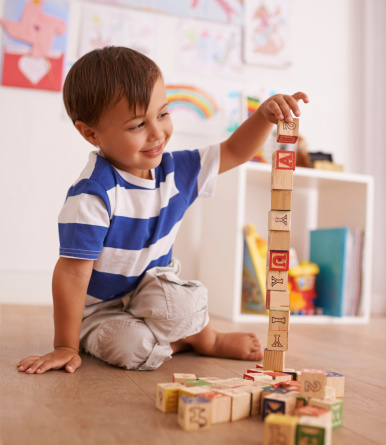 A young boy playing with his building blocks in his room