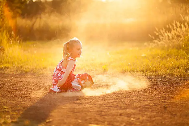 little girl playing in the dust with a stick
