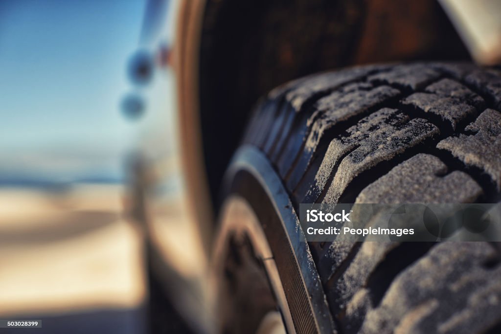 These tyres eat up any terrain Shot of a heavy duty 4x4 driving along some sand dunes Tire - Vehicle Part Stock Photo