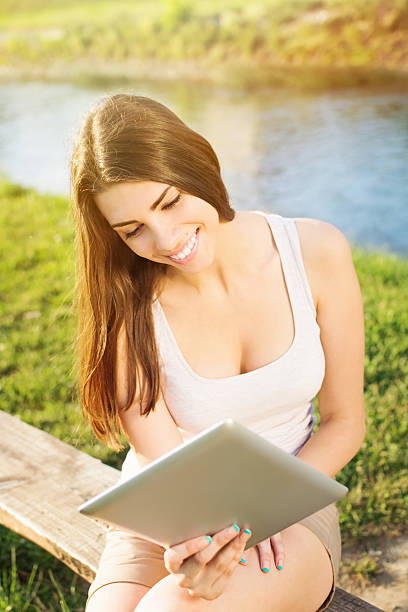 istock Pretty young woman with digital tablet sitting by the river 503039061