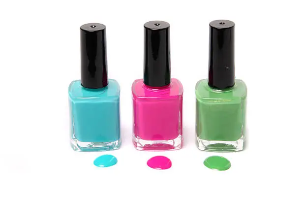 Nail polish bottles and spots in bright spring or summer colors in light blue, pink and green on a white background